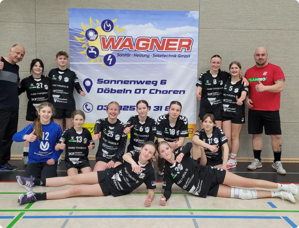 Mädchen-Handballmannschaft des Roßweiner SV mit beiden Trainern vor dem Sponsoren-Banner